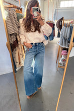 Load image into Gallery viewer, A woman takes a mirror selfie in a clothing boutique, wearing a light pink and white plaid long-sleeve shirt tucked into high-waisted, wide-leg blue denim jeans with a faded wash.