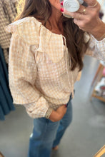 Load image into Gallery viewer, A woman takes a mirror selfie wearing a cream and white gingham eyelet blouse with a large ruffled collar, paired with blue jeans in a retail store setting.