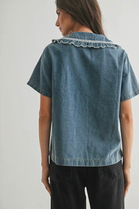 Woman wearing a denim shirt with lace trim on a plain background