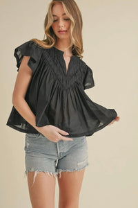 Woman wearing a black top and denim shorts on a beige background