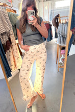 Load image into Gallery viewer, A woman takes a mirror selfie in a clothing boutique, wearing a gray short-sleeve top and cream wide-leg pants with a small bird print.