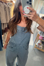 Load image into Gallery viewer, A woman takes a mirror selfie in a clothing store, wearing a blue and white vertically striped overall jumpsuit over a white top.