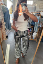 Load image into Gallery viewer, A woman takes a mirror selfie in a clothing boutique, wearing a white ribbed short-sleeve top and black-and-white gingham cropped pants with ruffled hems.