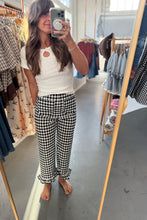 Load image into Gallery viewer, A woman takes a mirror selfie in a clothing boutique, wearing a white ribbed short-sleeve top and black-and-white gingham cropped pants with ruffled hems.