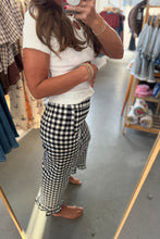 Load image into Gallery viewer, A woman takes a mirror selfie in a clothing store, wearing a white short-sleeve ribbed top and black-and-white gingham ruffled pants.