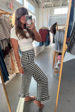 Load image into Gallery viewer, A woman takes a mirror selfie in a clothing boutique, wearing a white ribbed short-sleeve top and black-and-white gingham wide-leg pants with ruffled hems.