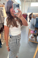 Load image into Gallery viewer, A woman takes a mirror selfie in a clothing store, wearing a white ribbed short-sleeve crop top and a black and white gingham wrap skirt.