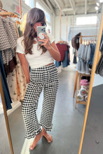 Load image into Gallery viewer, A woman takes a mirror selfie in a clothing boutique, wearing a white ribbed short-sleeve crop top and black-and-white gingham cropped pants with ruffled hems.