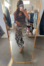 Load image into Gallery viewer, A woman takes a mirror selfie in a clothing boutique, wearing a dark gray ribbed tank top and high-waisted, loose harem-style pants with a gray, black, and orange floral pattern.