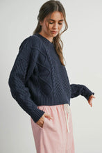Load image into Gallery viewer, Woman wearing a dark blue cable knit sweater with pink pants on a light background