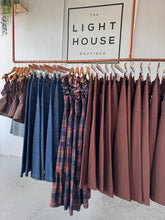 Load image into Gallery viewer, Stack of folded clothes on a rack with &#39;The Light House Boutique&#39; sign in the background