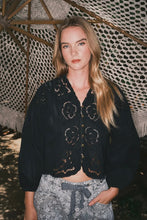 Load image into Gallery viewer, Woman wearing a black embroidered jacket and patterned pants standing under a textured canopy.