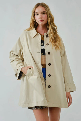 Woman wearing a beige coat on a plain background