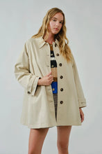 Load image into Gallery viewer, Woman wearing a beige trench coat against a plain background