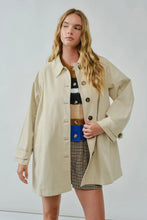 Load image into Gallery viewer, Woman wearing a beige trench coat over a patterned dress on a white background