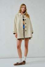 Load image into Gallery viewer, Woman wearing a beige trench coat over a patterned dress on a white background