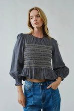 Load image into Gallery viewer, Woman wearing a black and white checkered blouse with puffed sleeves and blue jeans on a plain background