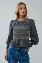 Load image into Gallery viewer, Woman wearing a black and white checkered blouse with a peplum waist and blue jeans on a plain background