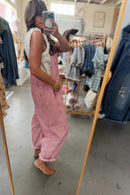 Load image into Gallery viewer, A woman takes a mirror selfie in a clothing boutique, wearing pink denim overall with a white ruffled sleeveless top underneath. Clothing racks and a mirror are visible in the background.