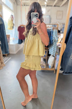 Load image into Gallery viewer, A woman takes a mirror selfie in a clothing boutique wearing a light yellow tiered ruffle dress with a matching skirt. The boutique has clothing racks, a mirror, and a gray floor.