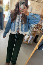 Load image into Gallery viewer, A woman takes a mirror selfie in a clothing boutique wearing a light blue denim jacket with white lace trim and dark green wide-leg pants.