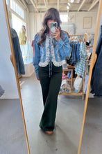 Load image into Gallery viewer, A woman takes a mirror selfie in a clothing boutique wearing a light blue denim jacket with white lace trim over a dark green wide-leg pants set.