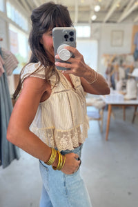 Woman taking a mirror selfie wearing a lace top and jeans in a store.