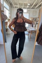 Load image into Gallery viewer, Person taking a mirror selfie wearing a brown top and black pants in a store.