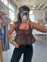 Load image into Gallery viewer, Woman taking a mirror selfie wearing a brown checkered top and black pants in a store.