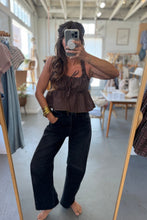 Load image into Gallery viewer, Person taking a mirror selfie wearing a brown top and black pants in a clothing store.