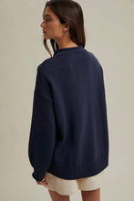 Load image into Gallery viewer, Woman wearing a navy sweater and beige shorts on a plain background