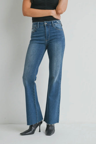 Person wearing blue jeans and black top on a plain background