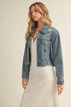 Load image into Gallery viewer, Woman wearing a denim jacket over a white dress on a beige background