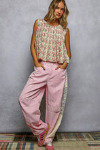 Load image into Gallery viewer, Woman wearing a floral top and pink pants against a gray background