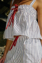 Load image into Gallery viewer, Person wearing a white and blue striped outfit with red accents.