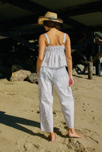 Load image into Gallery viewer, Person wearing a striped outfit and straw hat on a sandy beach.