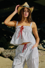 Load image into Gallery viewer, Woman wearing a striped outfit and cowboy hat on a beach