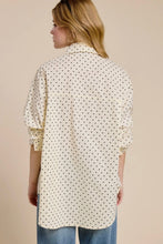 Load image into Gallery viewer, Woman wearing a long, patterned shirt with rolled-up sleeves against a beige background