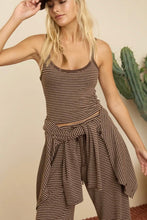 Load image into Gallery viewer, A woman modeling a brown and beige striped two-piece set consisting of a cropped tank top and matching high-waisted wrap pants, with a cactus in the background.