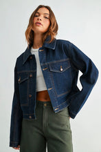Load image into Gallery viewer, A woman wearing a cropped dark blue denim jacket over a white crop top and olive green pants, photographed against a light gray studio background.