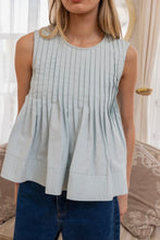 Load image into Gallery viewer, Woman wearing a light blue pleated top and dark jeans indoors.