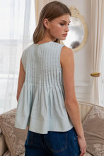 Load image into Gallery viewer, Woman wearing a light blue sleeveless top in a room with curtains and a mirror.