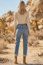 Load image into Gallery viewer, Person wearing a beige top and blue jeans standing in a desert landscape