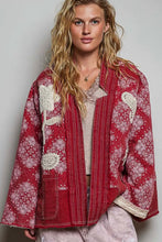 Load image into Gallery viewer, A woman wearing a red patchwork jacket with white floral prints and cream vertical stripes, styled over a beige top and light gray pants against a neutral gray background.