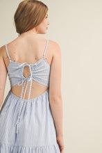 Load image into Gallery viewer, Woman wearing a light blue striped dress with cut-out back on a beige background