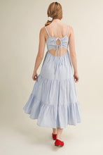Load image into Gallery viewer, Woman wearing a light blue striped dress with an open back on a beige background