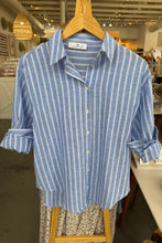 Load image into Gallery viewer, Blue and white striped shirt on a hanger in a store setting