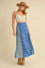 Load image into Gallery viewer, Woman wearing a white lace top and blue floral skirt with a beige hat on a beige background