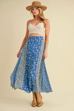 Load image into Gallery viewer, Woman wearing a white crop top, blue floral skirt, and brown hat on a beige background