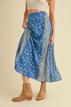 Load image into Gallery viewer, Woman wearing a blue floral skirt with a beige background